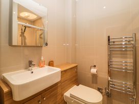A bathroom with a sink toilet mirror towel rack and hand soap at Apartment 4 10 Somers Court Paignton