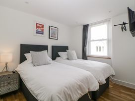 A bedroom with two single beds a window bedside table with lamp and wall-mounted television at Apartment 4 10 Somers Court in Paignton