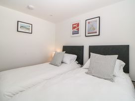 A bedroom with two single beds with white bedding and striped pillows and framed pictures on the walls at Apartment 4 10 Somers Court in Paignton