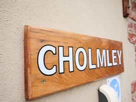 A wooden sign with the text CHOLMLEY attached to a wall at Chomley @ Summerfield Farm in Hawsker