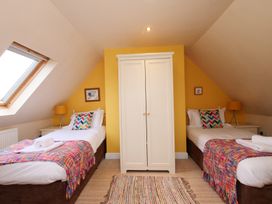 A bedroom with two beds and a wardrobe at Chomley @ Summerfield Farm in Hawsker