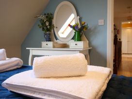 A bedroom with towels on a bed and a dresser with flowers at Chomley @ Summerfield Farm Hawsker