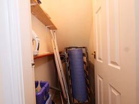 A utility room with an ironing board and a shelf with cleaning supplies at Chomley @ Summerfield Farm in Hawsker