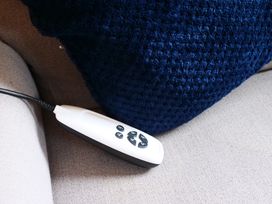A remote control next to a blue cushion on a couch at Albany @ Summerfield Farm, Hawsker