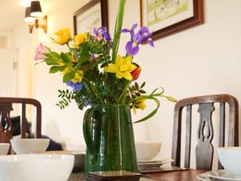 A dining room with flowers in a vase and table settings at Albany @ Summerfield Farm in Hawsker
