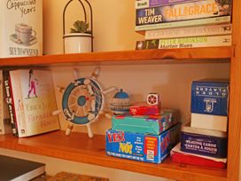 A shelf with books, a plant, and board games at Albany @ Summerfield Farm, Hawsker