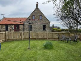 A garden with a table and chairs in front of a house at Albany @ Summerfield Farm, Hawsker