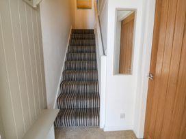 A hallway with stairs and a mirror at 4 Bryn Llan Aberdaron