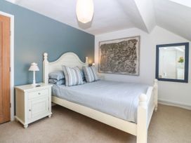 A bedroom featuring a bed, nightstand, and mirror at 4 Bryn Llan, Aberdaron