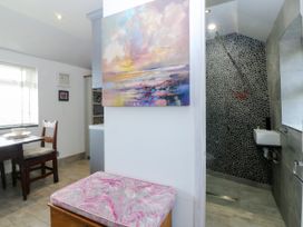 A dining area with a table and chair near a bathroom at 5 Bryn Llan Pwllheli