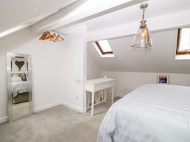 A bedroom with a bed, desk, and mirror at 5 Bryn Llan Pwllheli