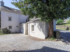 An exterior view of a house with a tree and gravel area at Bridge End Cottage Haverthwaite near Cartmel