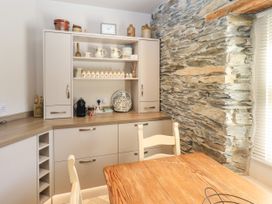 A kitchen with cabinets and a stone wall at Bridge End Cottage Haverthwaite near Cartmel