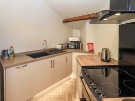 A kitchen with a sink stove kettle toaster and microwave at Bridge End Cottage in Haverthwaite near Cartmel