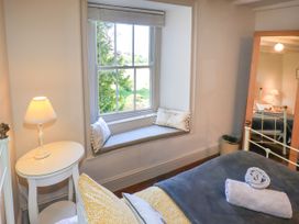 A bedroom with a window seat and a mirror at Bridge End Cottage in Haverthwaite near Cartmel