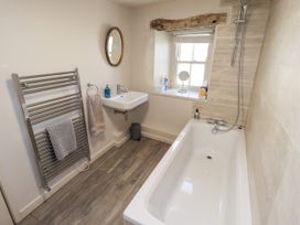 A bathroom with a bathtub, sink, and towel rack at Bridge End Cottage in Haverthwaite near Cartmel