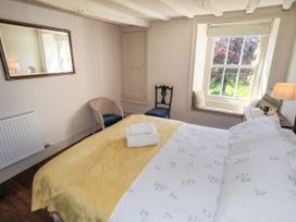 A bedroom with a bed and chairs at Bridge End Cottage Haverthwaite near Cartmel
