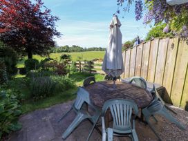 A garden with a table, chairs and an umbrella at Bridge End Cottage in Haverthwaite near Cartmel