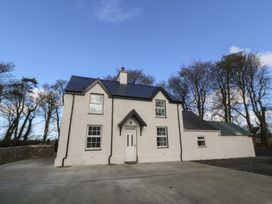 A house with a driveway and trees at Gate House, Capel Coch near Llanerchymedd