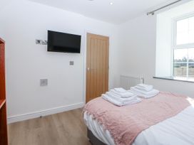 A bedroom with a bed and television at Gate House Capel Coch near Llanerchymedd