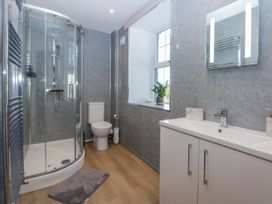 A bathroom featuring a shower, toilet, and sink at Gate House Capel Coch near Llanerchymedd