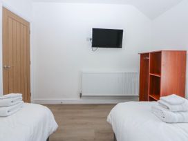 A bedroom with two beds and a television mounted on the wall at Gate House Capel Coch near Llanerchymedd