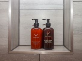 A bathroom shelf with shampoo and conditioner bottles at The Cadeleigh near Tiverton