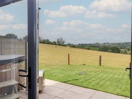 A view from an outdoor patio showing a field and hot tub at The Cadeleigh near Tiverton