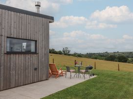 An outdoor space with a wooden building and seating area at The Cadeleigh in Cadeleigh near Tiverton