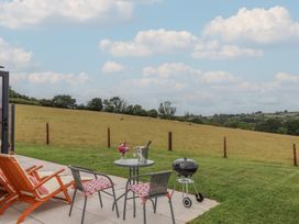 A garden with a table and chairs and a grill at The Cadeleigh in Cadeleigh near Tiverton