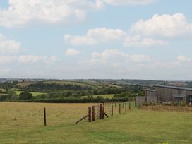 A view of a field with trees and a building at The Cadeleigh near Tiverton