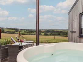 An outdoor area with a hot tub and chairs overlooking the countryside at The Pennymoor in Cadeleigh near Tiverton