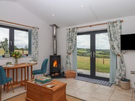 A living room with a stove and dining table at The Pennymoor Cadeleigh near Tiverton