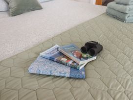 A bedroom with books and binoculars on the bed at The Pennymoor in Cadeleigh near Tiverton