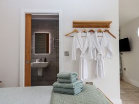 A bedroom with a bed and bathrobes hanging at The Pennymoor in Cadeleigh near Tiverton