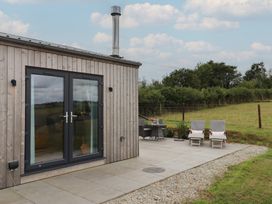 An outdoor area with a wooden building and patio furniture at The Pennymoor in Cadeleigh near Tiverton