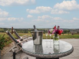 An outdoor area with a table, chairs, and a view of fields at The Pennymoor in Cadeleigh near Tiverton