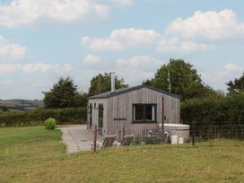 A wooden house with a pathway and grass area at The Pennymoor Cadeleigh near Tiverton