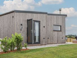 An outdoor view of a wooden house with plants and gravel at The Bickleigh Cadeleigh near Tiverton