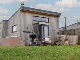 A wooden cabin with outdoor seating and a hot tub at The Bickleigh in Cadeleigh near Tiverton
