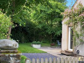 A garden with trees, rock, chair, and patio at Greywalls in Maulds Meaburn
