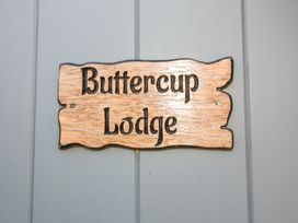 A wooden sign with the text Buttercup Lodge mounted on a gray wall at Buttercup Lodge in Misterton