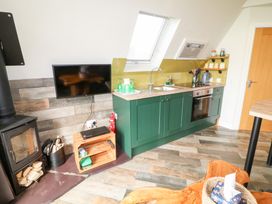 A kitchen with green cabinets wood stove and wall mounted television at Buttercup Lodge in Misterton
