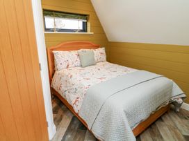 A bedroom with a wooden bed frame a window above the headboard and green walls at Buttercup Lodge in Misterton