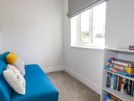 A snug with a blue sofa and bookshelf at Chi Gwynn in Crantock