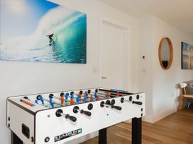A living room with a foosball table and surfboard artwork at Chi Gwynn in Crantock