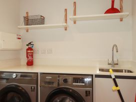 A laundry room with a washing machine, dryer, and sink at Chi Gwynn in Crantock