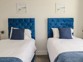 A bedroom with twin beds and a decorative picture at Chi Gwynn in Crantock