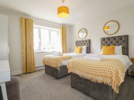 A bedroom with twin beds and a desk at Chi Gwynn in Crantock