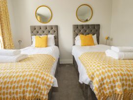 A bedroom with two beds and yellow decor at Chi Gwynn in Crantock